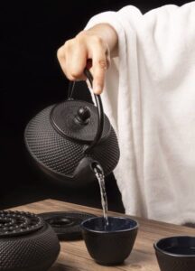 Water being poured from a black cast iron teapot